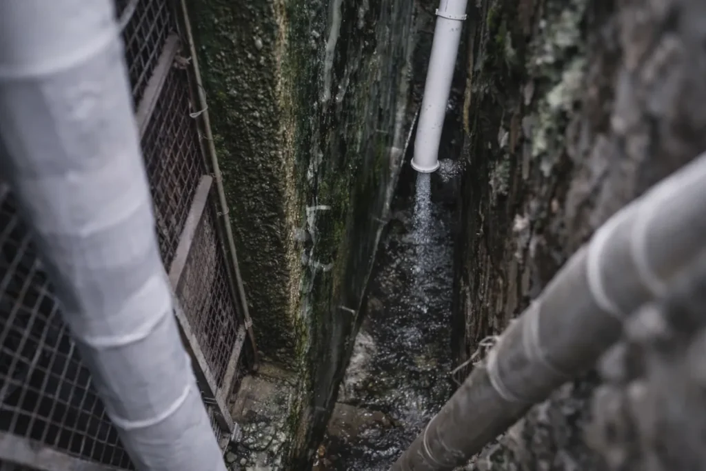 narrow damp alley with drainpipe and moisture-stained walls